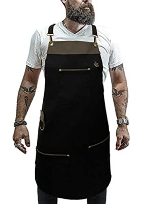 Homem vestindo avental preto de cozinheiro com bolsos, alça para panos e detalhes em couro. 